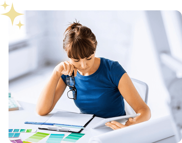 A woman sitting at a table with papers and a phone.